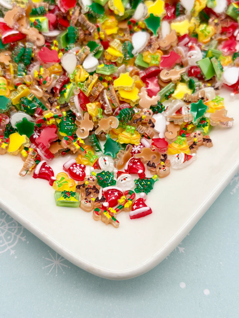 A white plate filled with a variety of colorful, festive-themed candies, including Christmas-themed candies and other holiday-related decorations.