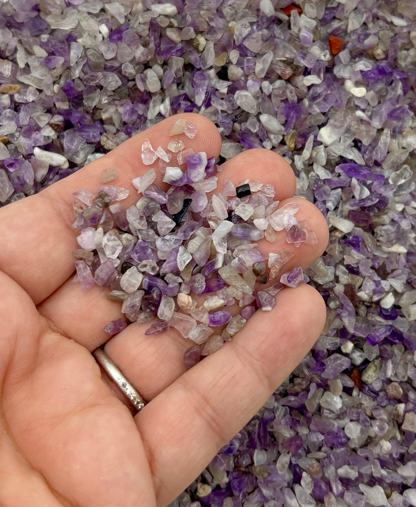 a person holding a handful of purple and white crystals