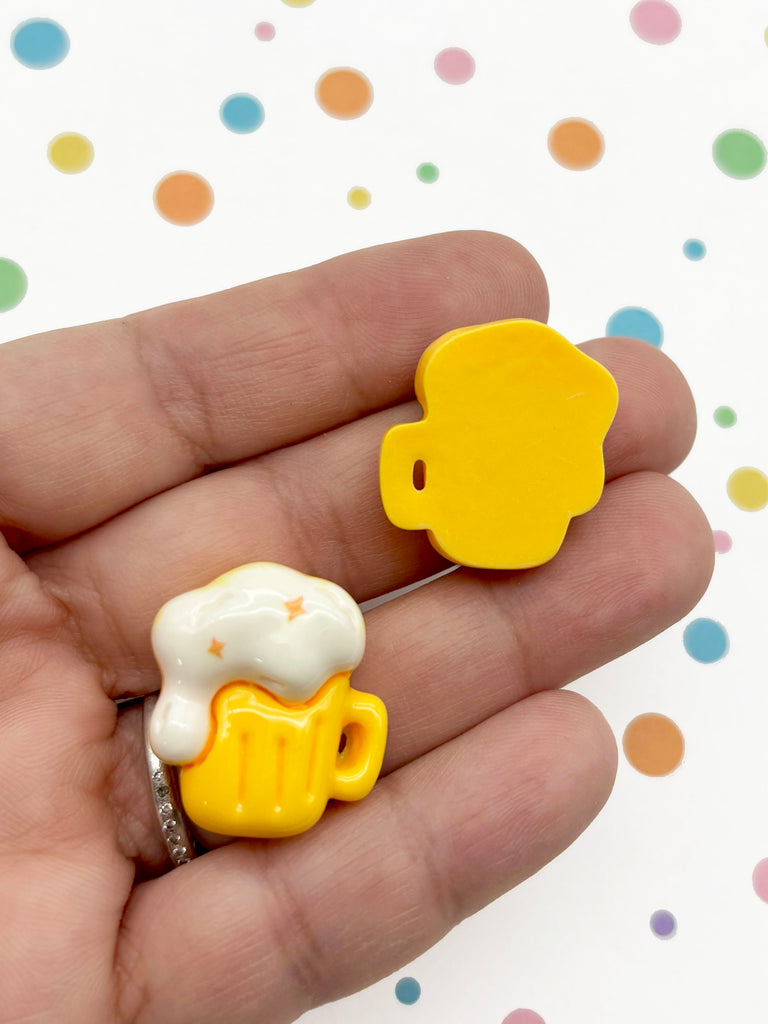 A hand holding two yellow beer mug-shaped objects against a background with colorful polka dots.