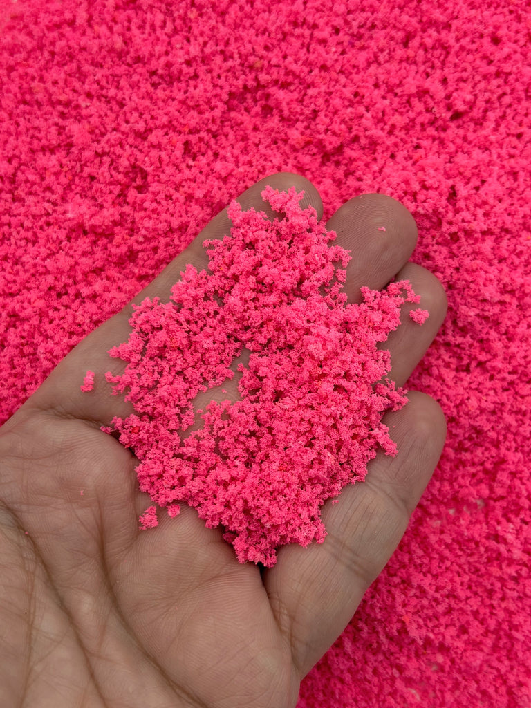 a hand holding a pile of pink sand