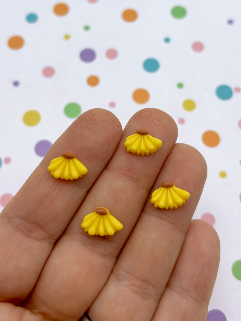 a hand holding a pair of yellow earrings