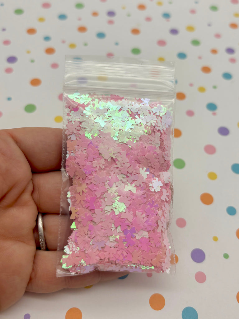 a hand holding a small bag of pink and silver confetti