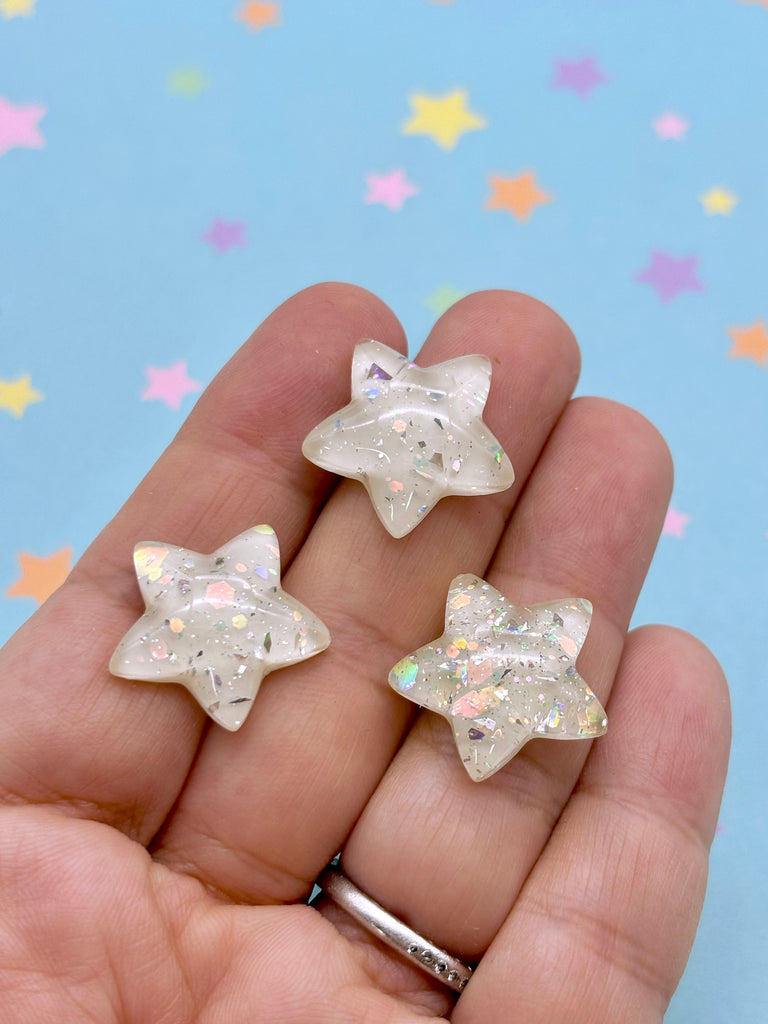 a person holding two small white stars in their hand