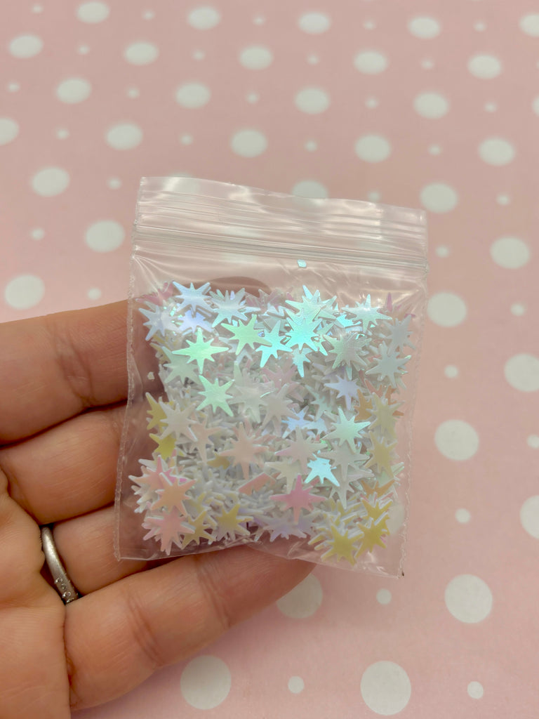 a hand holding a bag of white and silver stars