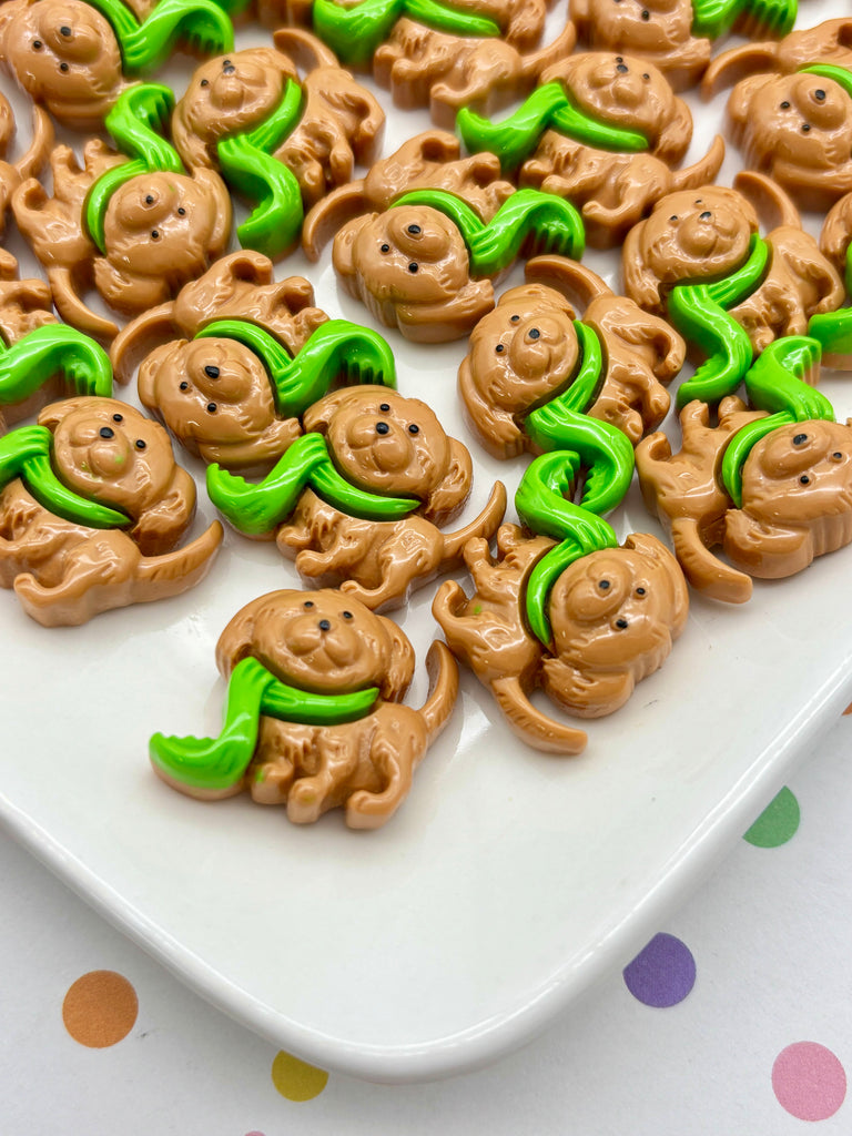 a collection of brown toy animals with green accessories, such as tongues, arranged on a white surface.