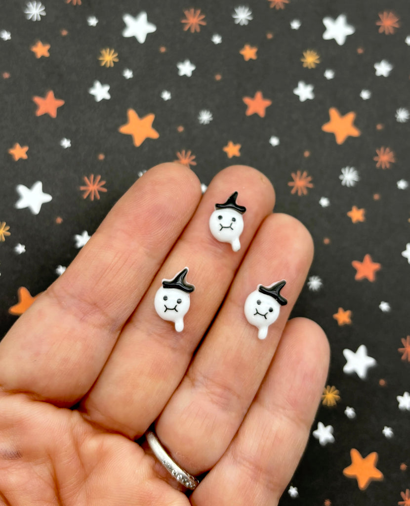 a hand holding a pair of small white and black earrings