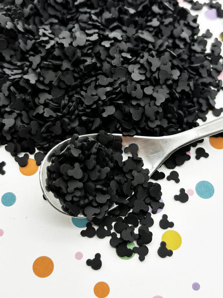 a spoon filled with black confetti on top of a table