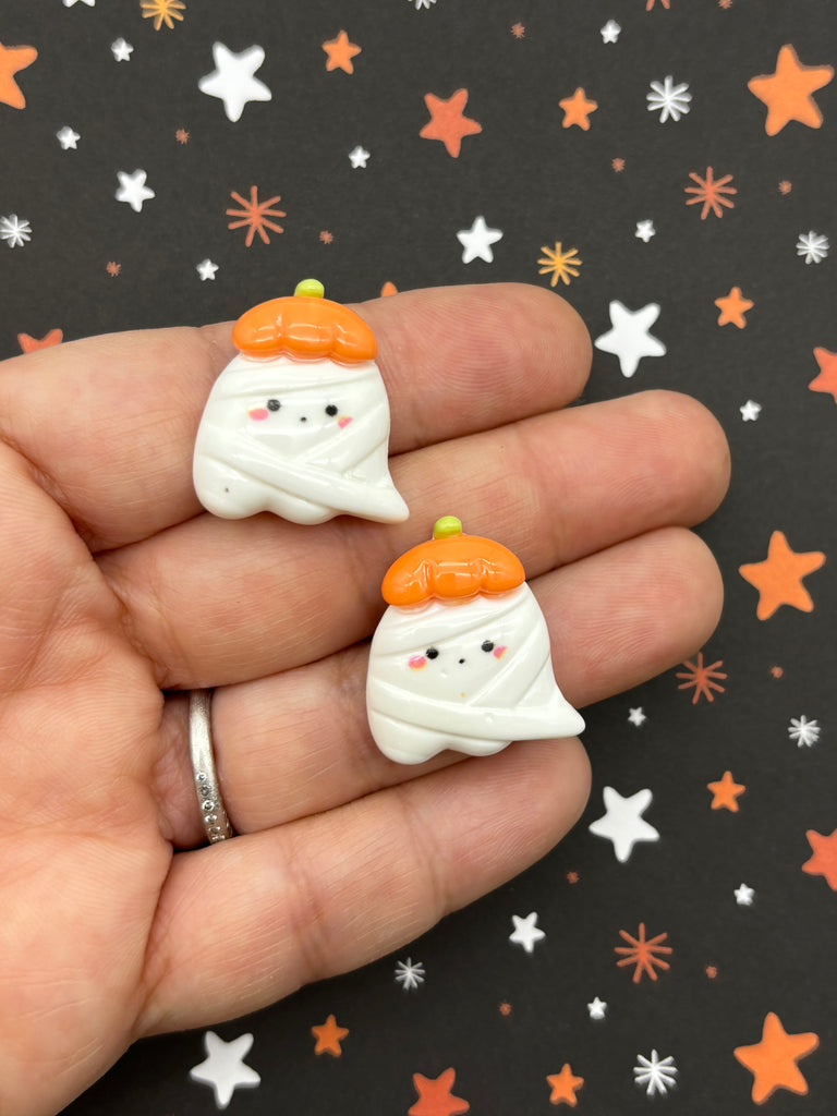 a hand holding two small white and orange snowmen