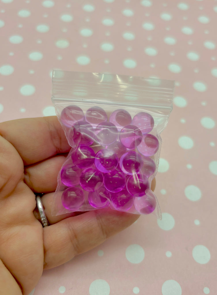 a hand holding a bag of purple plastic buttons