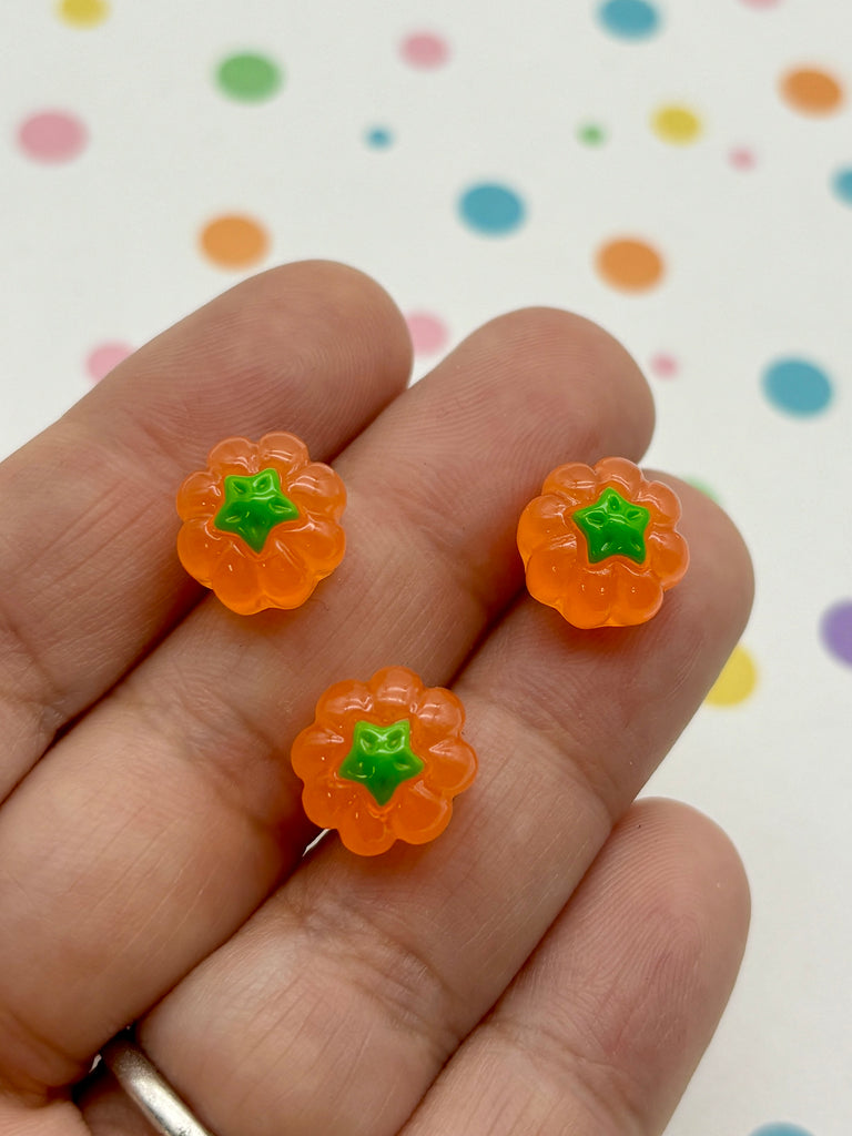 a hand holding three small orange gummy bears