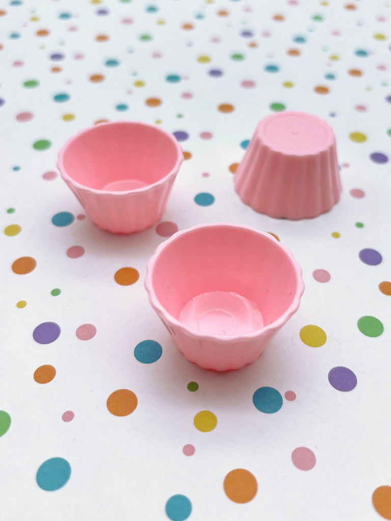 three pink cups sitting on top of a table