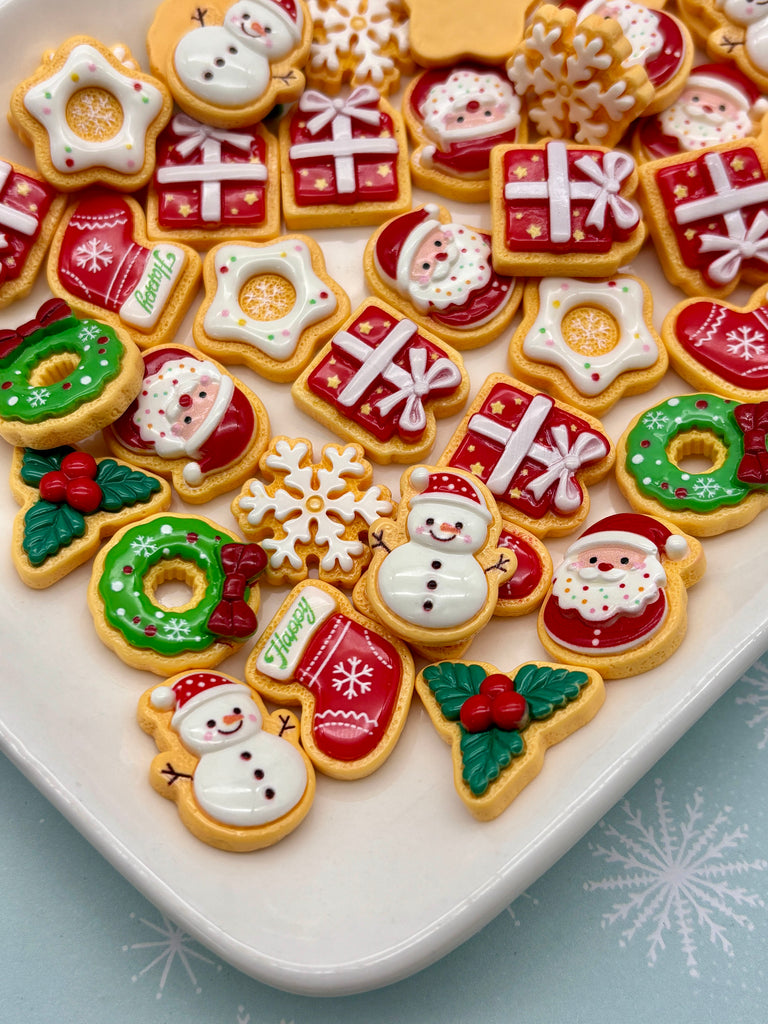 A white plate filled with an assortment of Christmas-themed cookies, including Santa Claus, snowmen, presents, and other festive decorations.