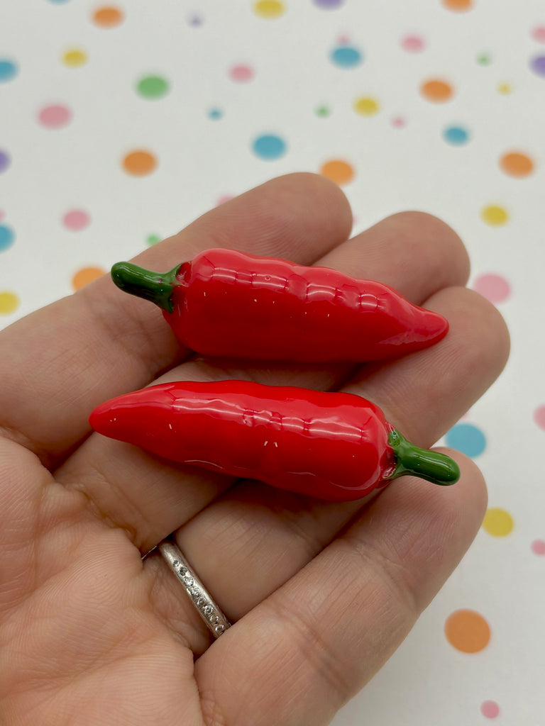 a person holding two red peppers in their hand