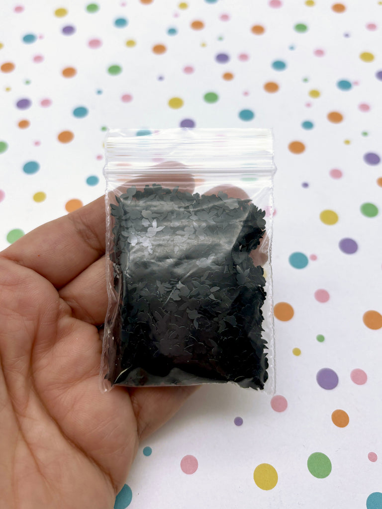 a hand holding a small bag of black stuff