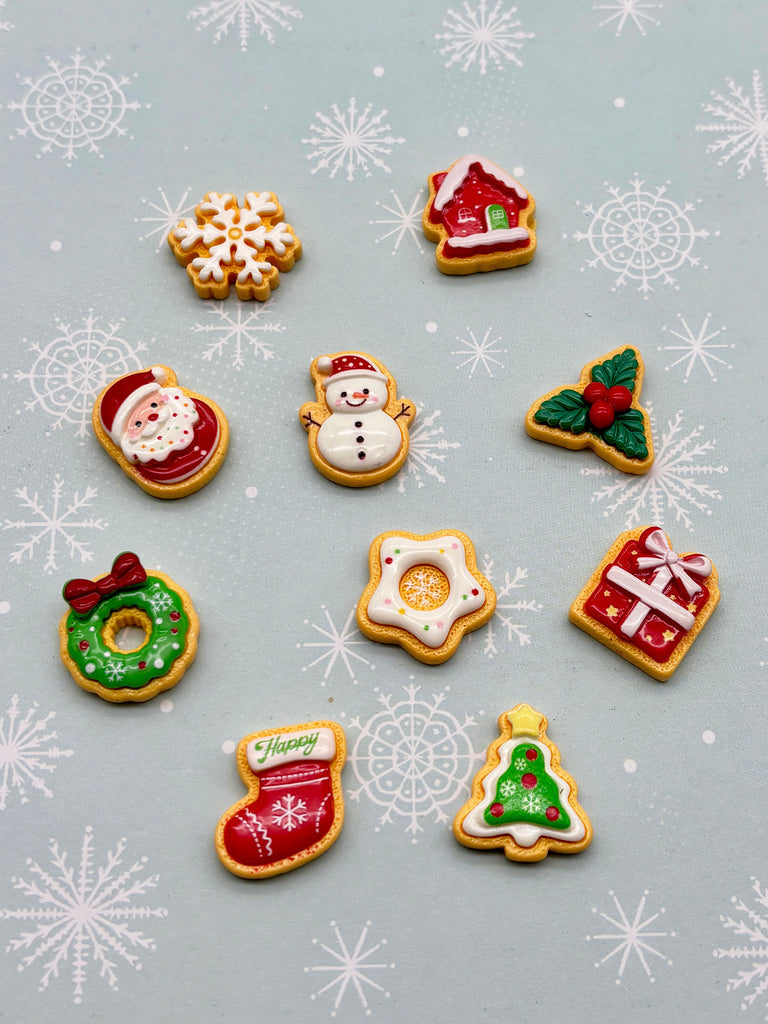 a collection of festive Christmas-themed cookies and decorations, including a Santa Claus cookie, a snowman cookie, a star cookie, a gift cookie, a wreath cookie, a stocking cookie, a Christmas tree cookie, and a star cookie.
