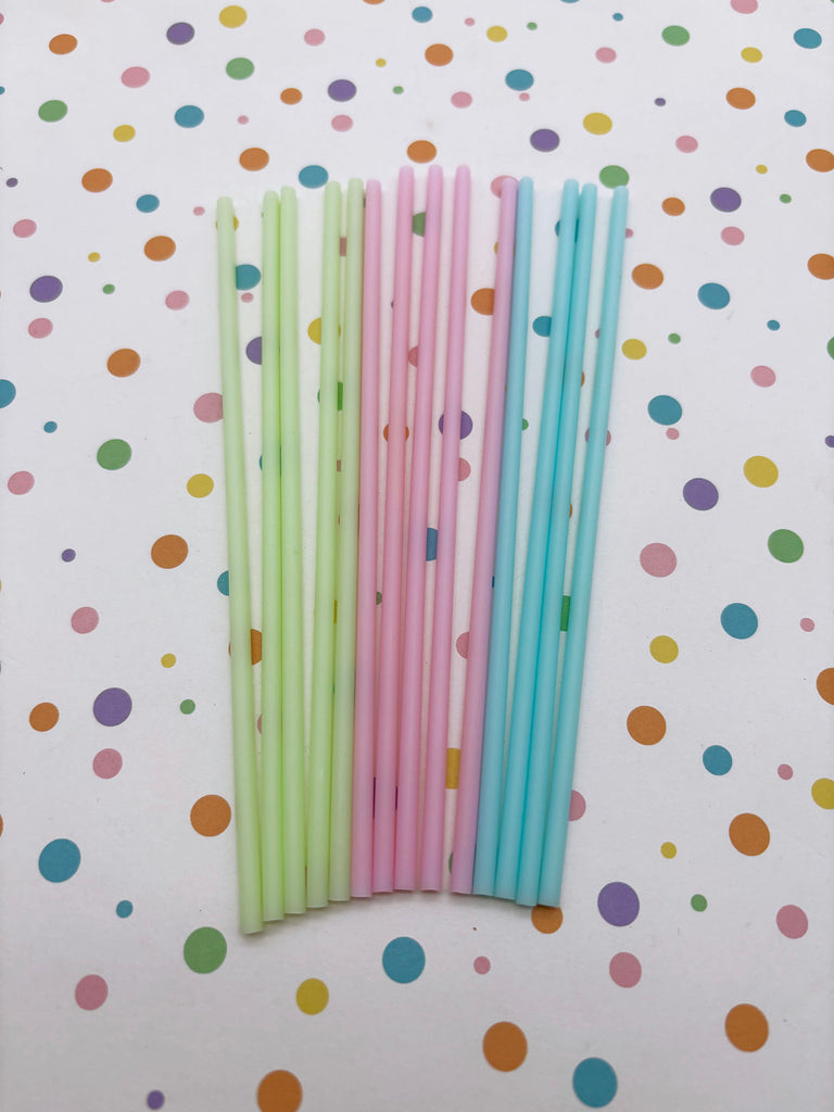 A collection of colorful straws in various pastel shades, including green, pink, and blue, arranged on a white background with a polka dot pattern.