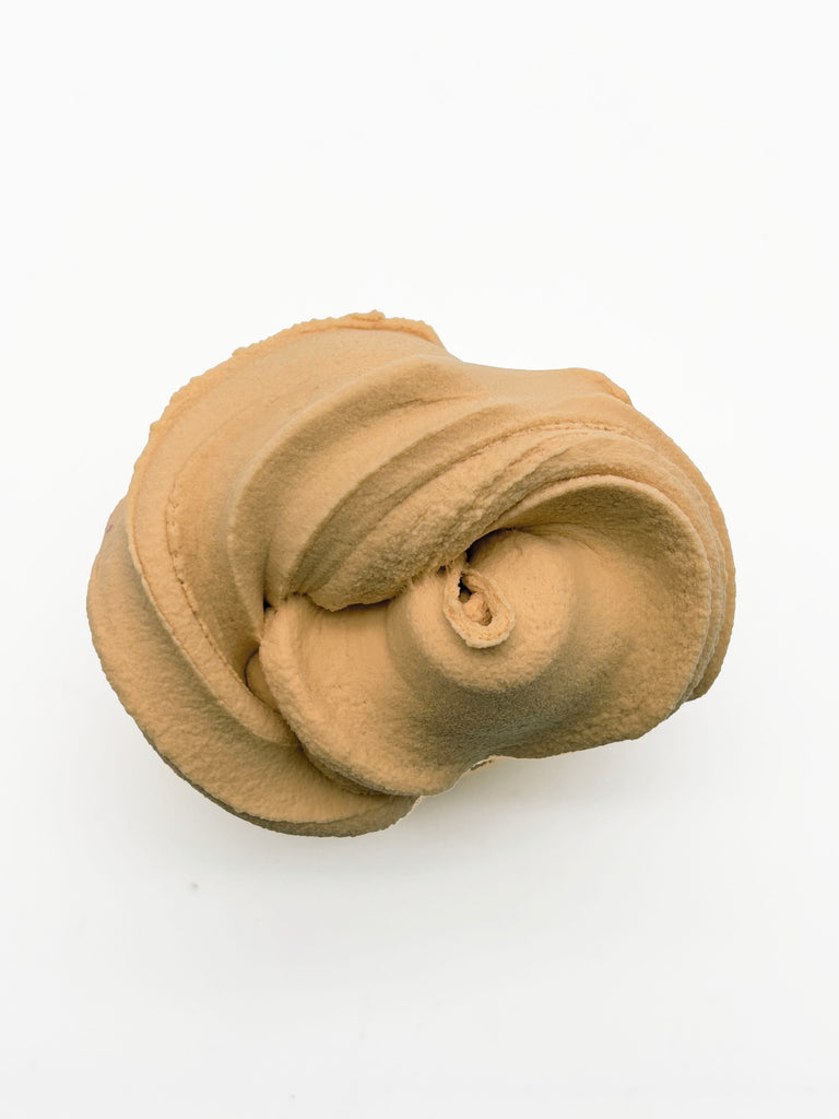 A single, light brown, crumpled object resembling a piece of fabric or a small, curled item is shown against a plain white background.