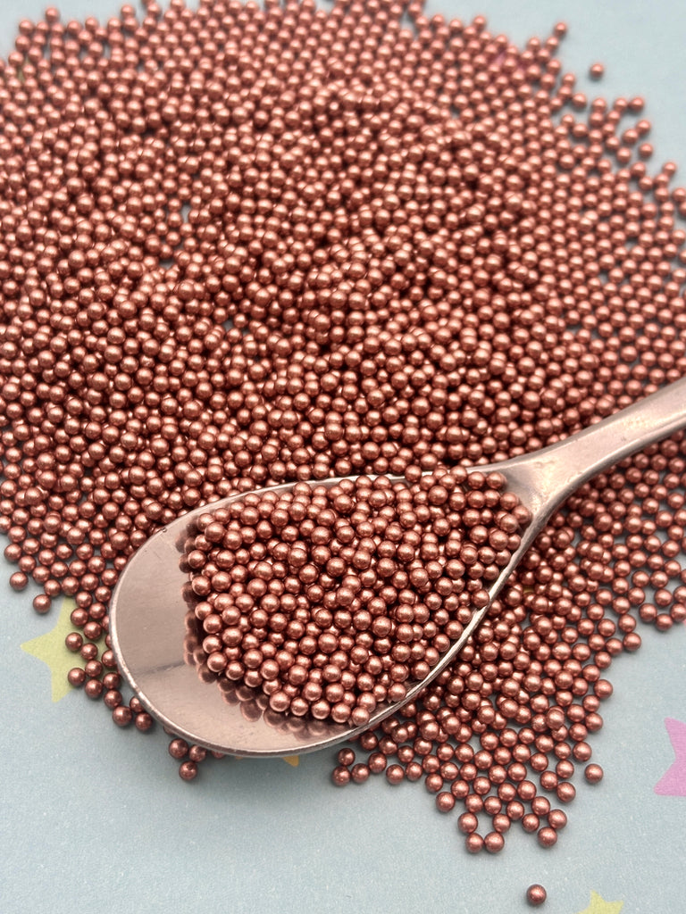 a spoon full of metallic beads on a blue surface