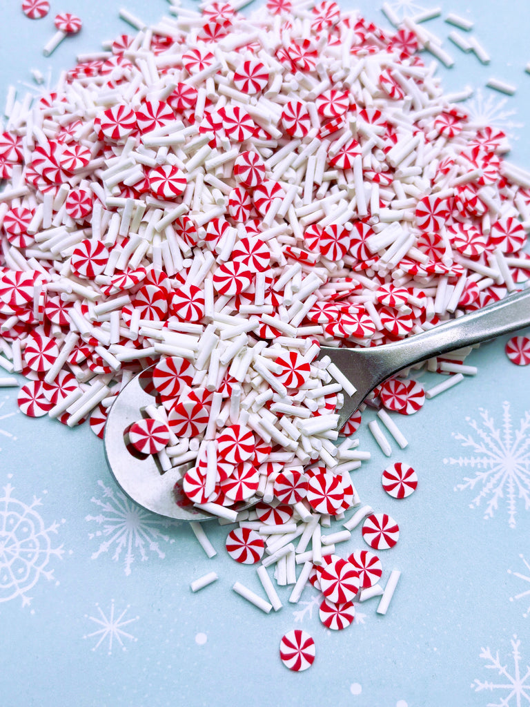 a pile of red and white sprinkles next to a pair of scissors