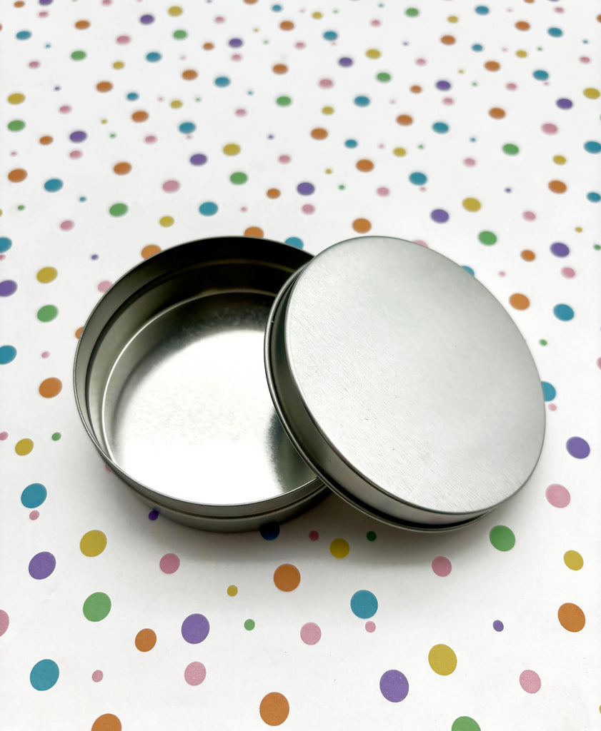 two tins sitting on top of a table covered in confetti