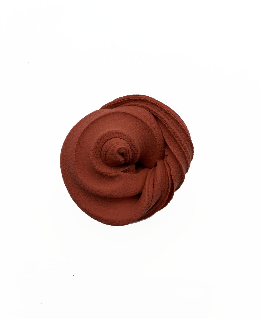 A single, round, brown object resembling a flower or a ball is shown against a white background.