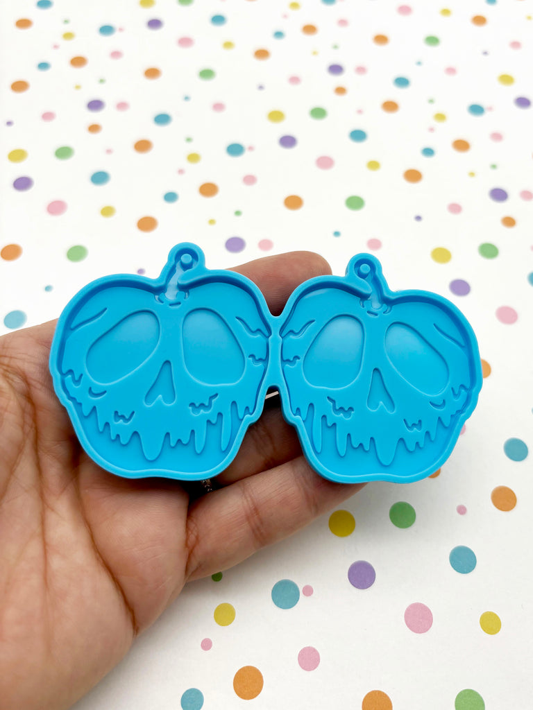 a hand holding two cookie cutters in the shape of elephants