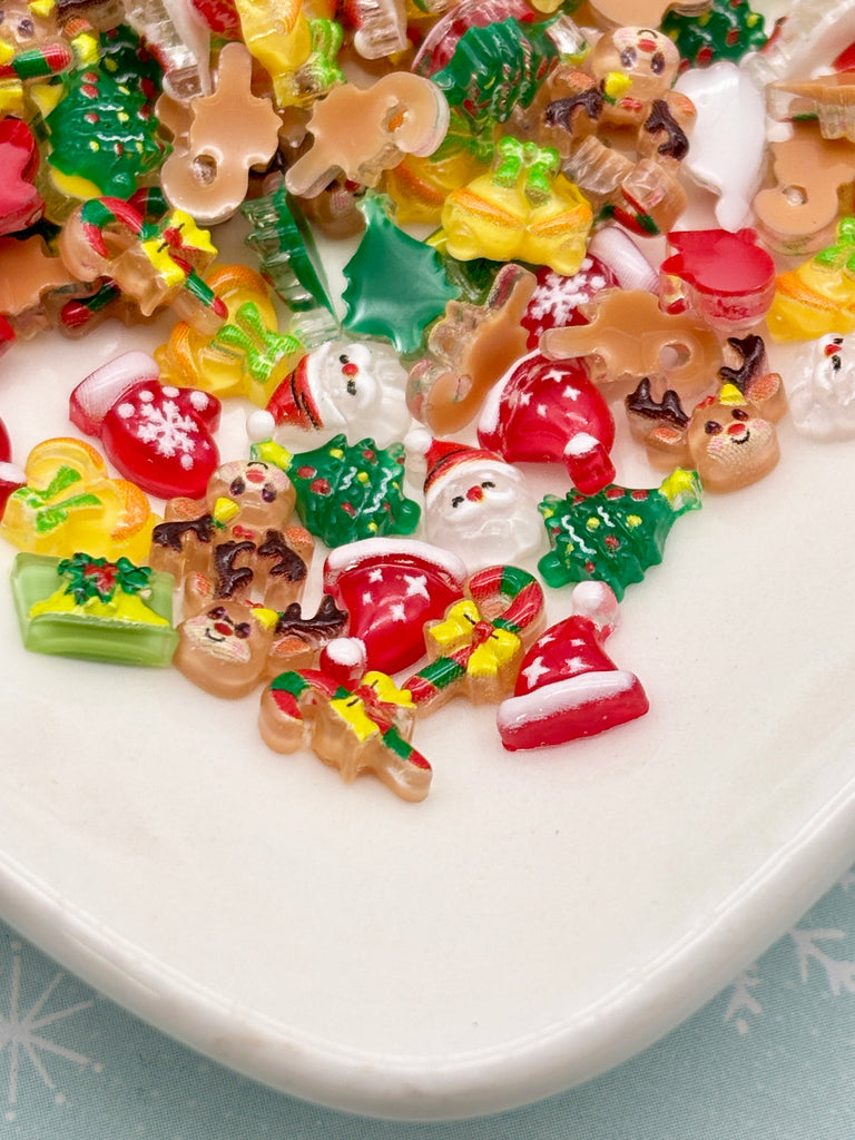 A plate filled with a variety of colorful and festive Christmas-themed candies, including candy canes, gingerbread men, snowmen, and other holiday-themed decorations.