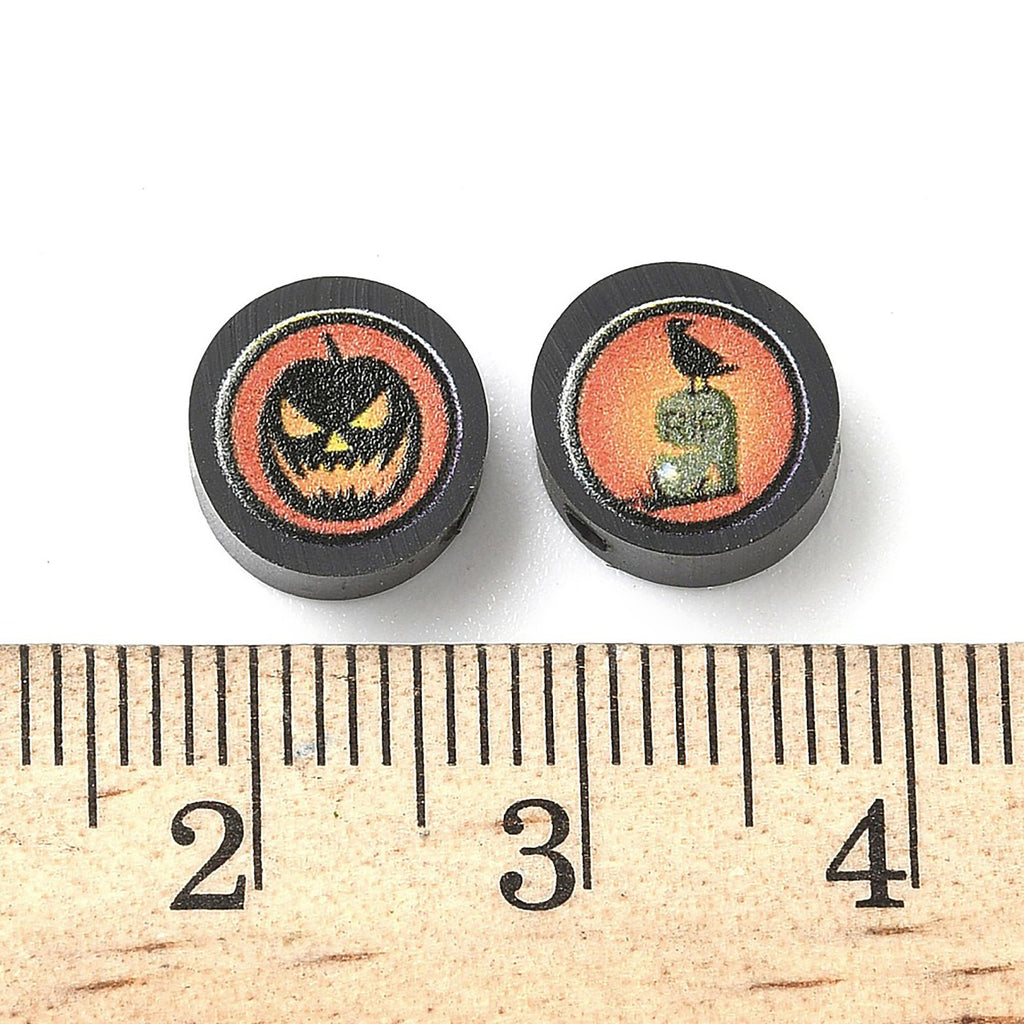 two Halloween-themed beads, each with a different design, placed next to a ruler for size comparison.
