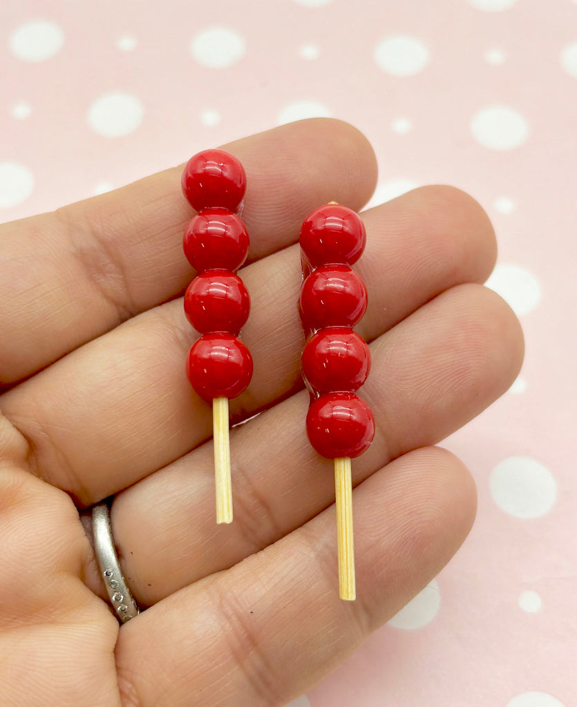 a person holding a pair of red candy lollipops