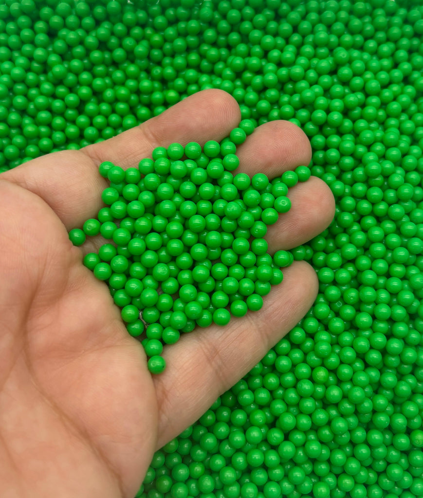 a hand holding a handful of green beads