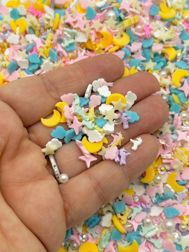 a hand holding a pile of small stars and moon confetti