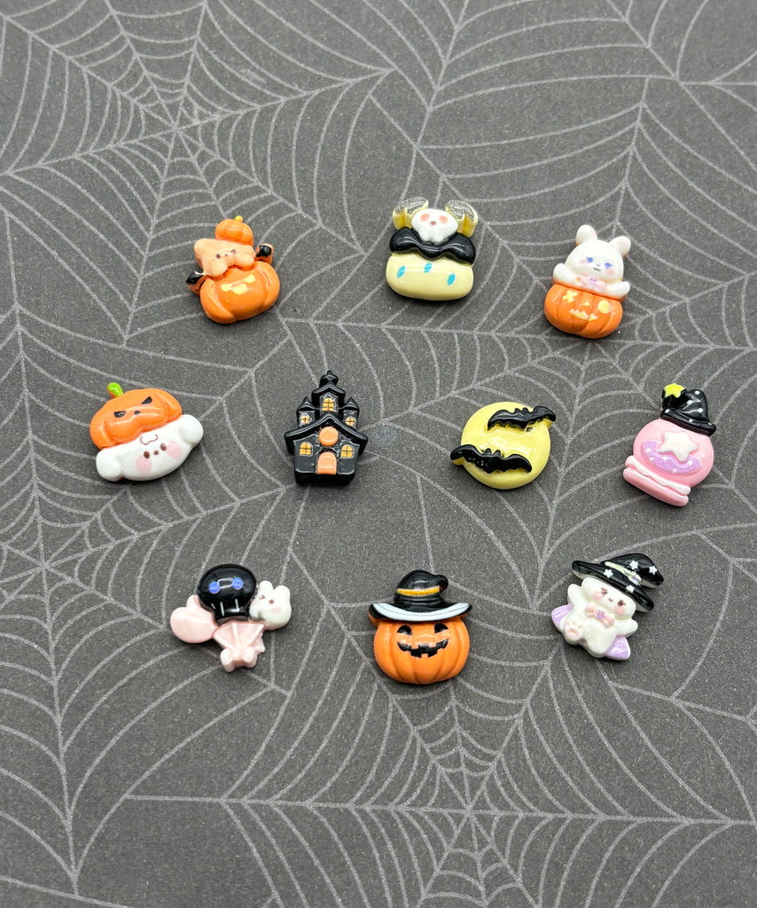 a collection of Halloween-themed small figurines and decorations arranged on a spider web patterned surface.