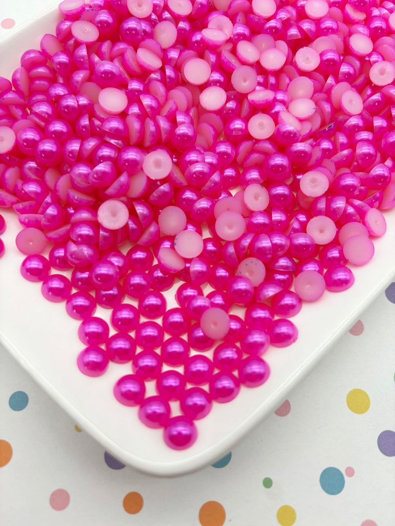 a white plate filled with numerous small, round, pink beads. The beads are scattered across the plate, creating a visually appealing and colorful display.