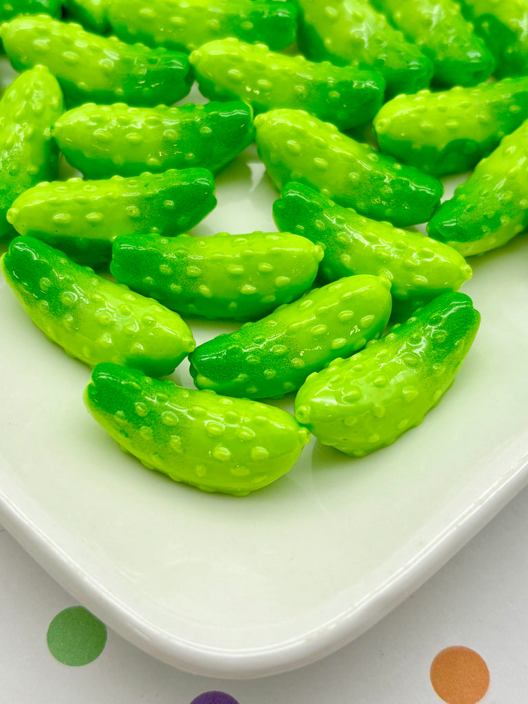 a white plate topped with green pickles on top of a table