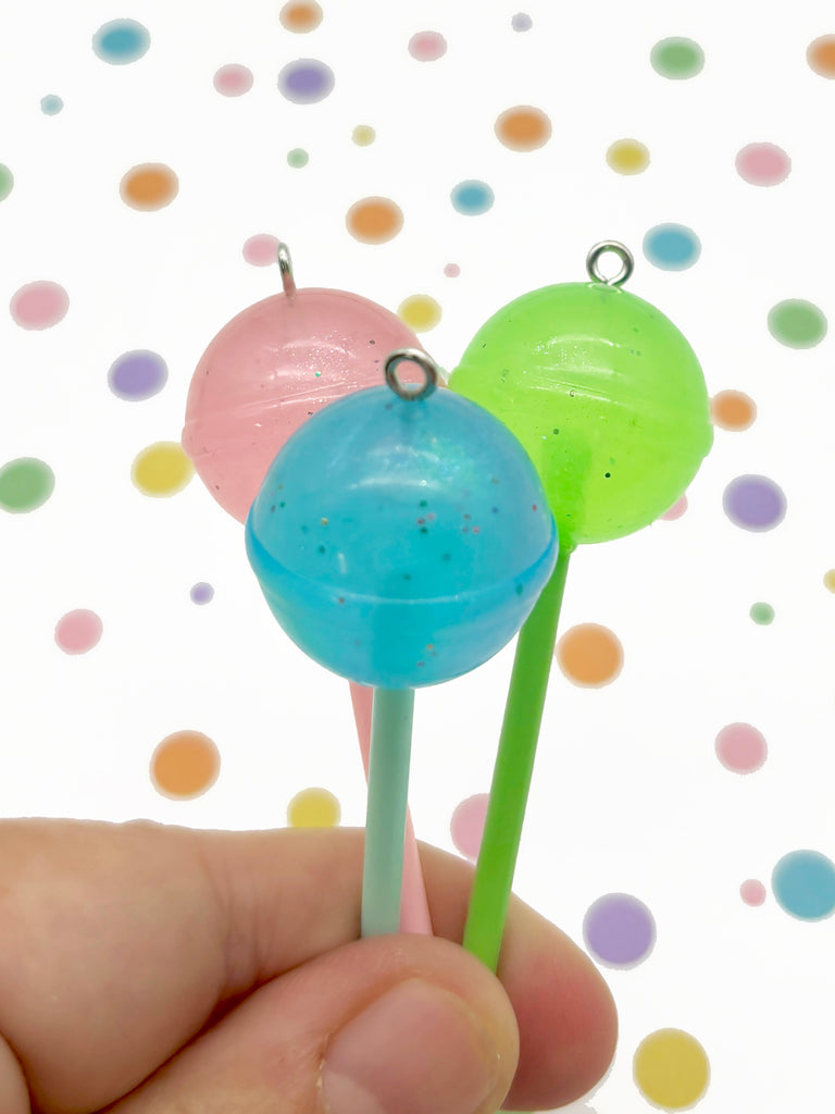 a hand is holding two lollipops in front of a white background