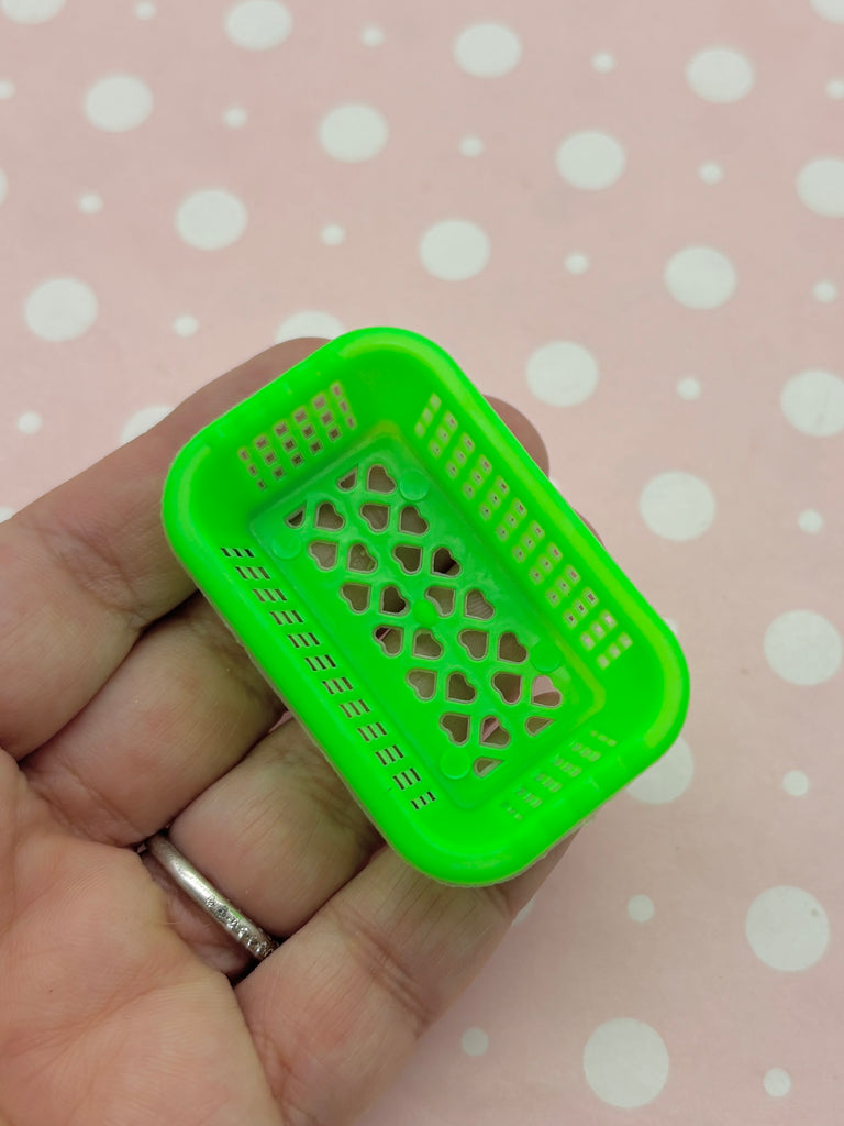 A hand holding a small green plastic basket with a patterned design.