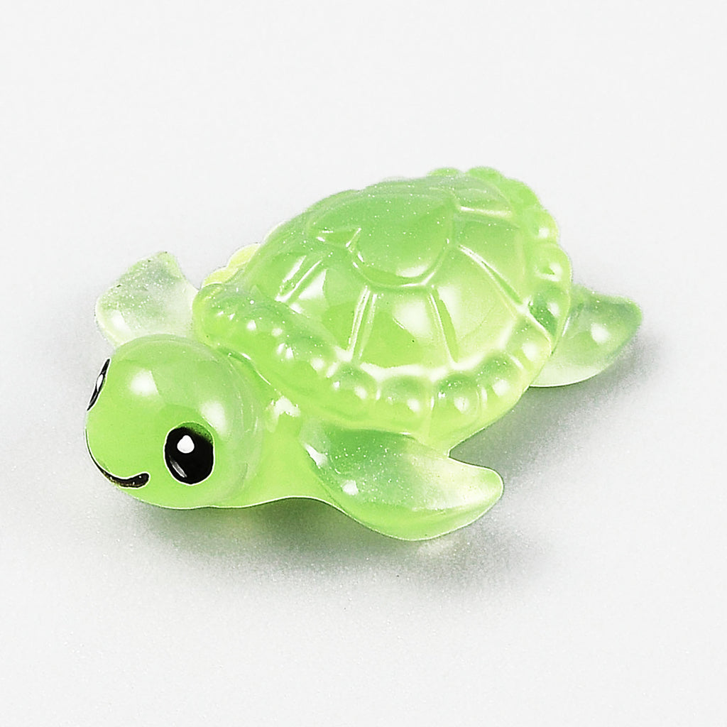 A small, green, glow-in-the-dark turtle toy is shown in the image.