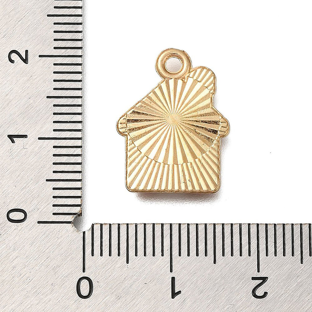A gold-colored house-shaped charm is placed next to a ruler for size comparison.