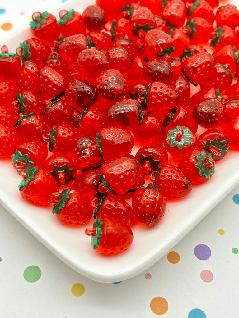 a white plate filled with numerous red plastic strawberries, arranged in a visually appealing manner.