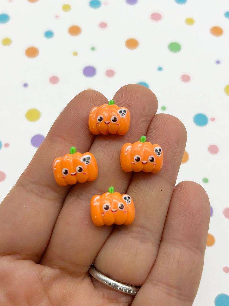 a hand holding five small orange pumpkins with googly eyes