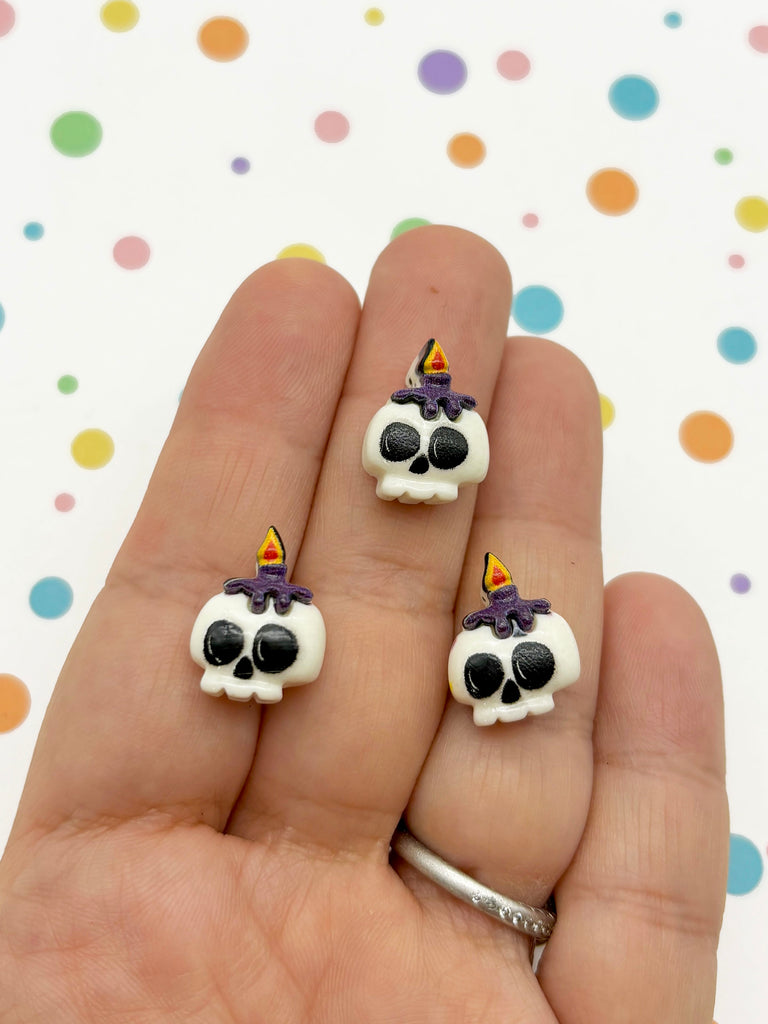 a hand holding three small skull shaped rings