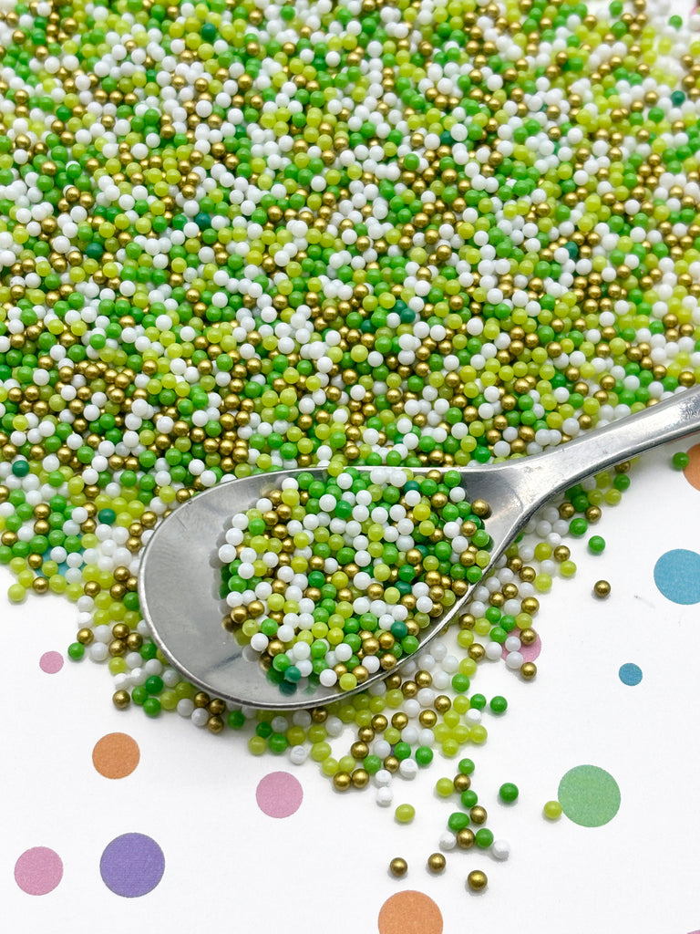 a scoop of green and white sprinkles next to a spoon