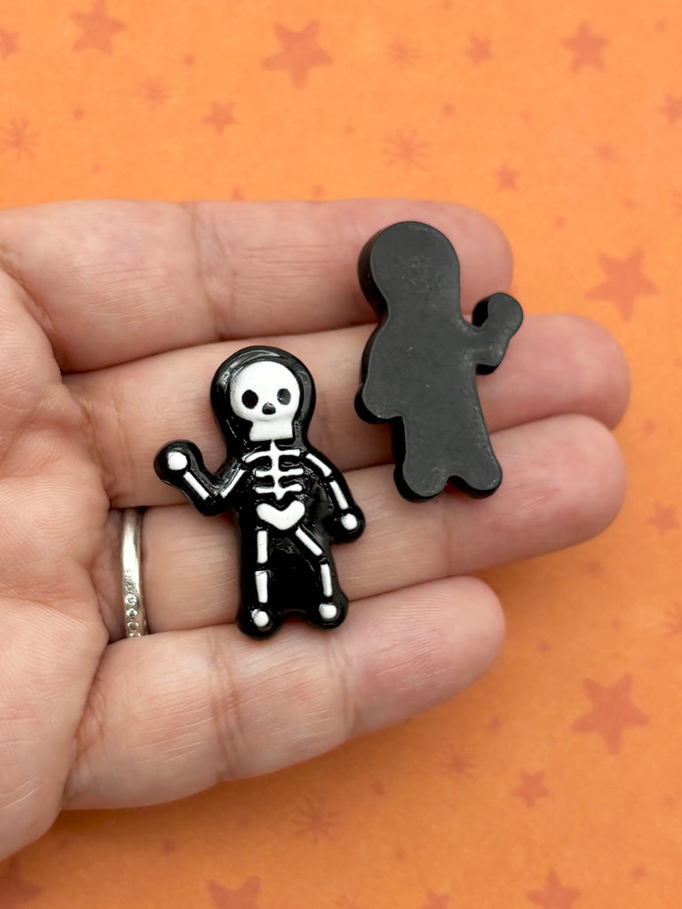 A hand holding two black, cartoon-like figures against an orange background with stars.