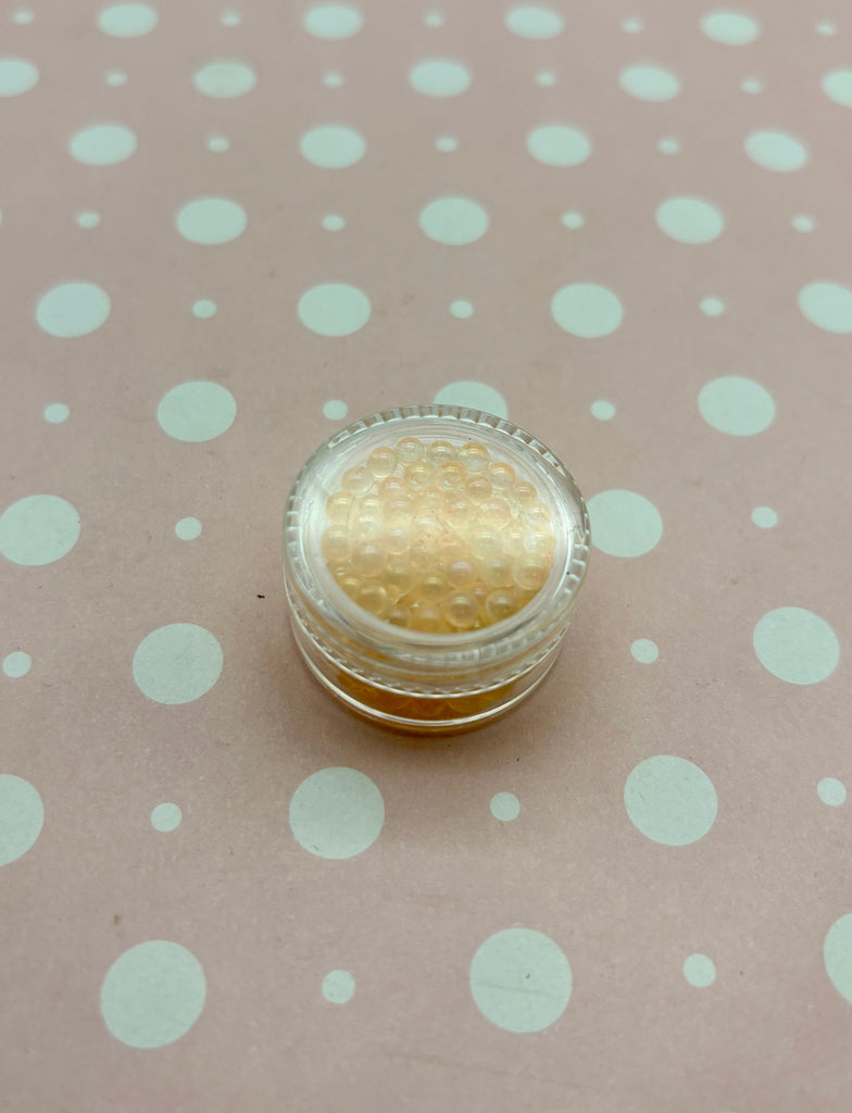 a small jar with a gold lid sitting on a polka dot tablecloth