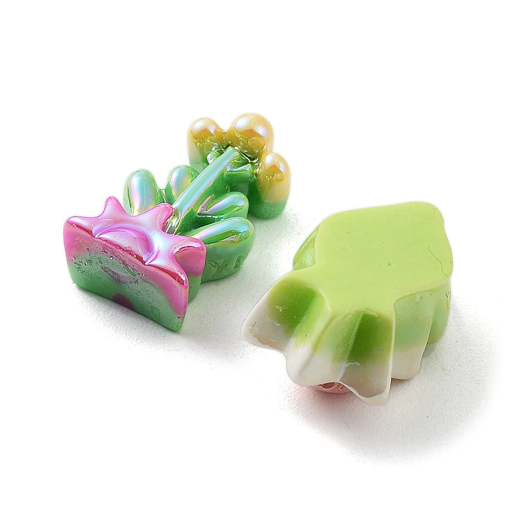three colorful, three-dimensional objects, including a pink and green flower-shaped object, a green and white fish-shaped object, and a green and white fish-shaped object.