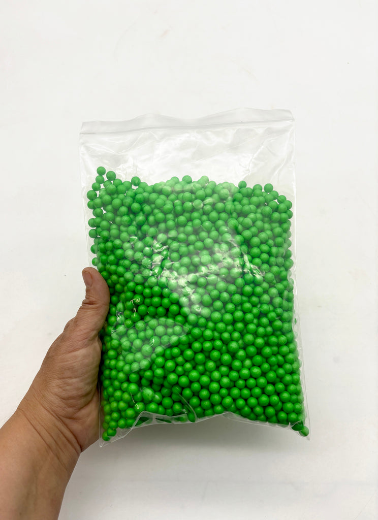 a hand holding a bag of green beads