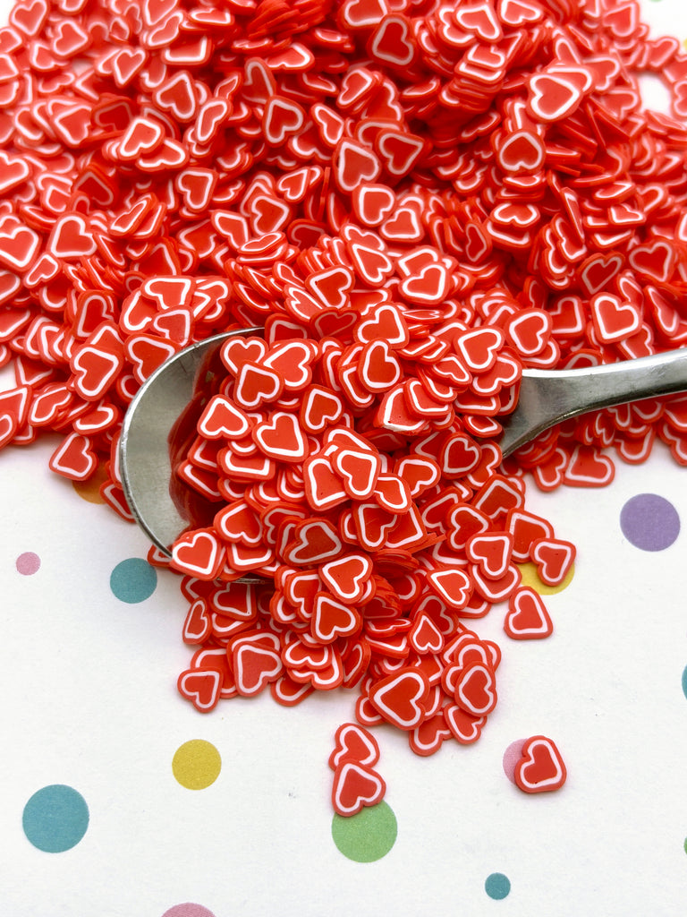 a pile of red and white hearts next to a spoon