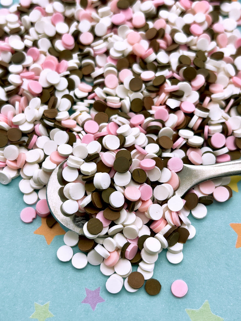 a spoon full of pink and brown sprinkles