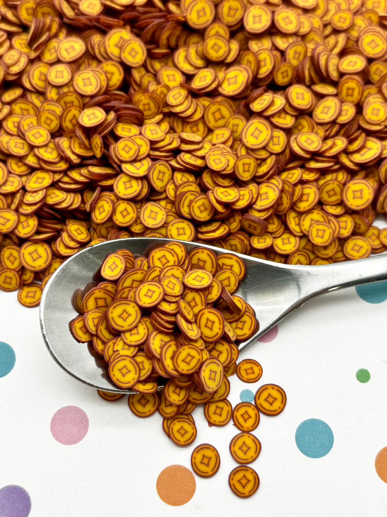 a spoon full of gold coins on a polka dot tablecloth