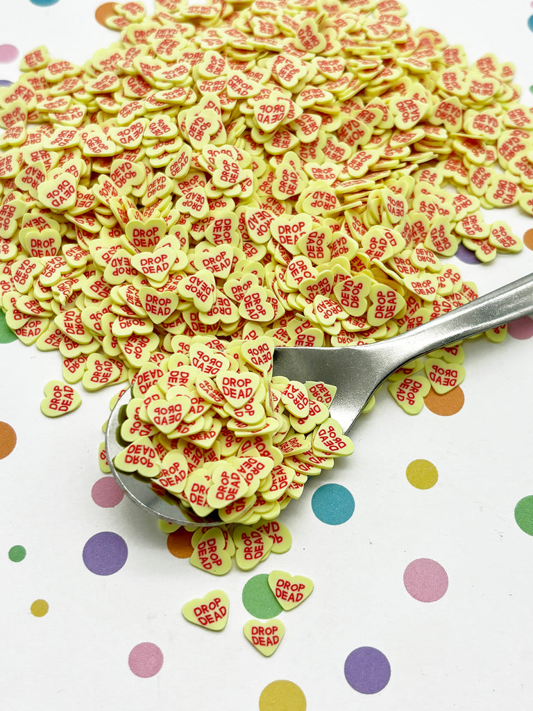 a pile of heart shaped confetti next to a spoon